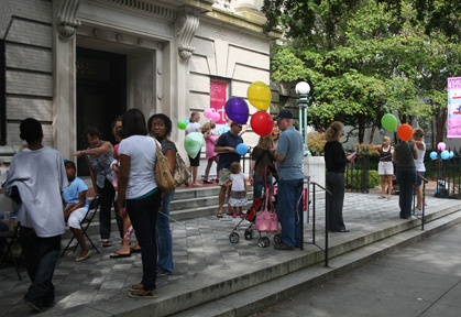 Visitors gather on the front steps to listen to banjo and guitar performers Lowcountry Bluegrass, to grab a balloon, and to get their face painted before moving inside