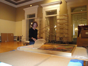 Collections Manager Zinnia Willits unwrapping a slip-cased painting