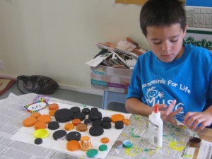 Alex creates a collage with recycled screw-caps during Go Green week.