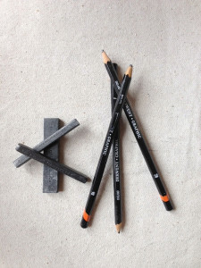 Drawing implements: graphite sticks, charcoal, and pencils.