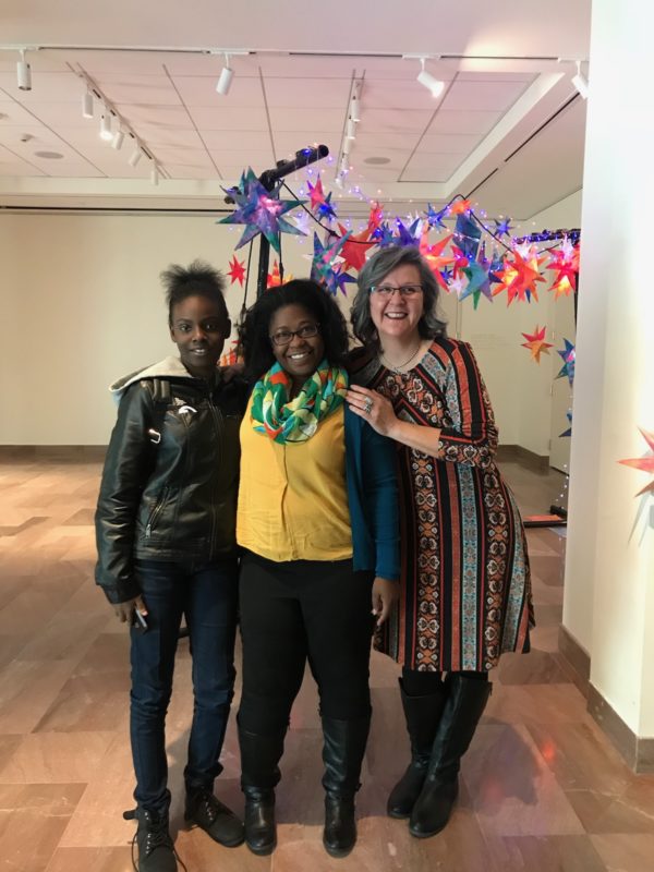 Marielena stands with a student from Simmons-Pinckney Middle School and Ms. Adeogun, her teacher, in front of their final artistic creation.
