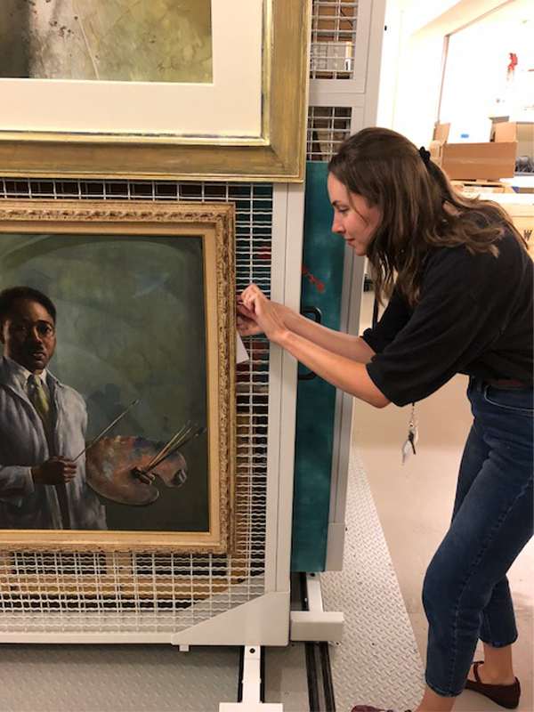Here, Hannah tags A Portrait of Aaron Douglas by Edwin Harleston with its accession number, or its unique identification number, so that staff can quickly search its information in the database.