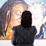 Woman looking at a painting of 2 women