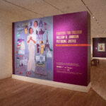Installation shot including a purple wall and title of show