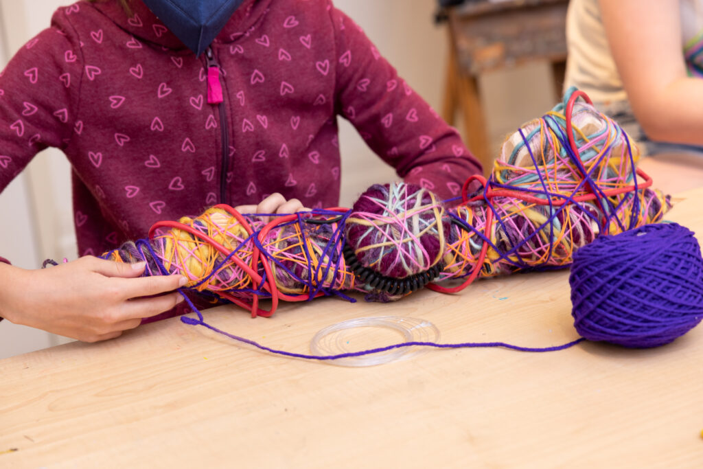 Girl wrapping yarn to create a sculpture
